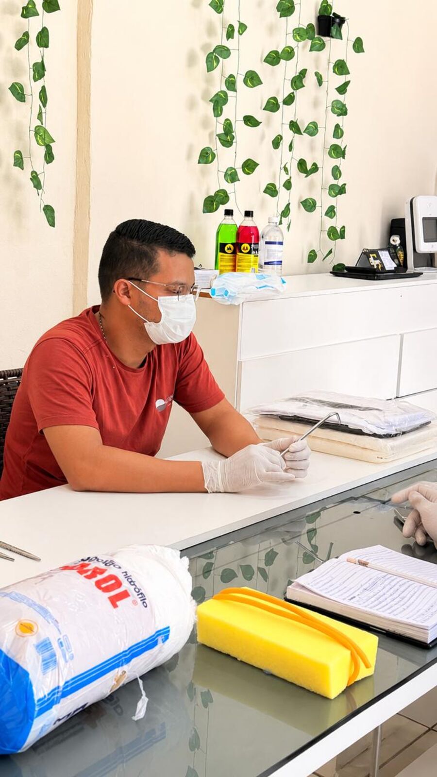 Aluno do curso de tanatopraxia prepara o instrumental na bancada, com luvas, máscara e óculos de proteção.